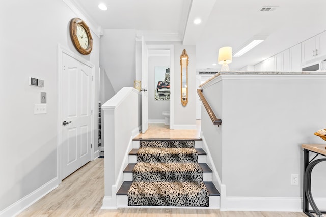 stairway with hardwood / wood-style flooring and crown molding