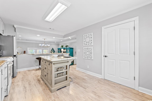 kitchen featuring light stone counters, a chandelier, pendant lighting, a center island, and electric range