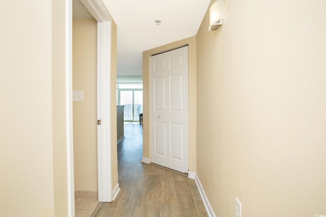 corridor with light wood finished floors and baseboards