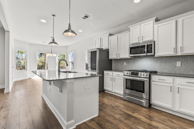 kitchen featuring pendant lighting, stainless steel appliances, an island with sink, white cabinets, and sink