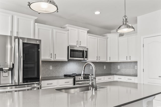 kitchen with pendant lighting, stainless steel appliances, tasteful backsplash, white cabinetry, and sink