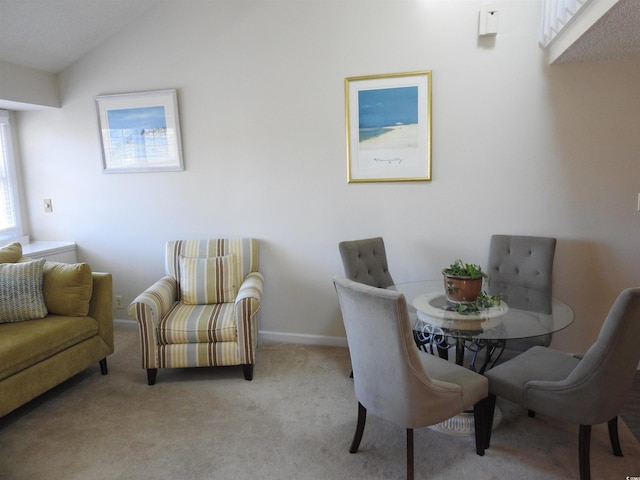 carpeted dining room featuring vaulted ceiling