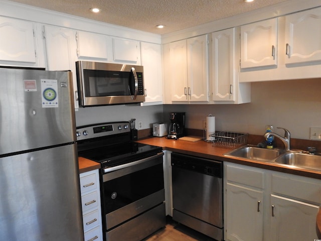 kitchen with sink, white cabinetry, a textured ceiling, and appliances with stainless steel finishes