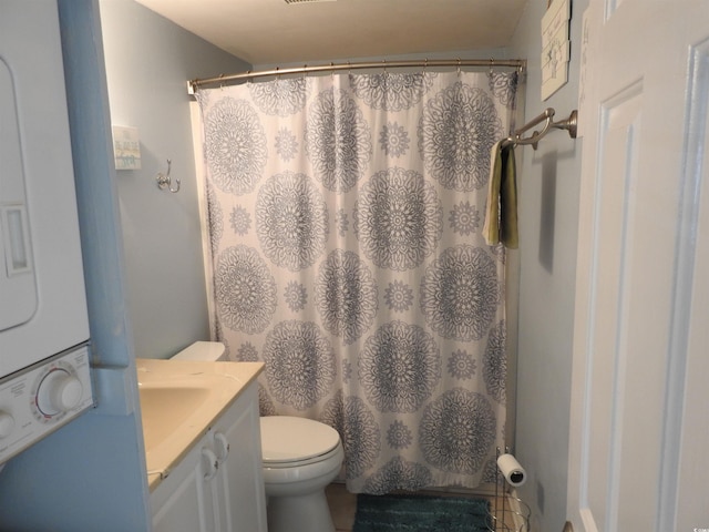 bathroom featuring a shower with curtain, toilet, stacked washer / drying machine, and vanity