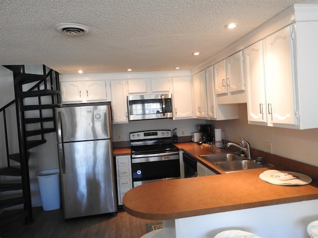 kitchen featuring appliances with stainless steel finishes, a textured ceiling, white cabinetry, sink, and kitchen peninsula