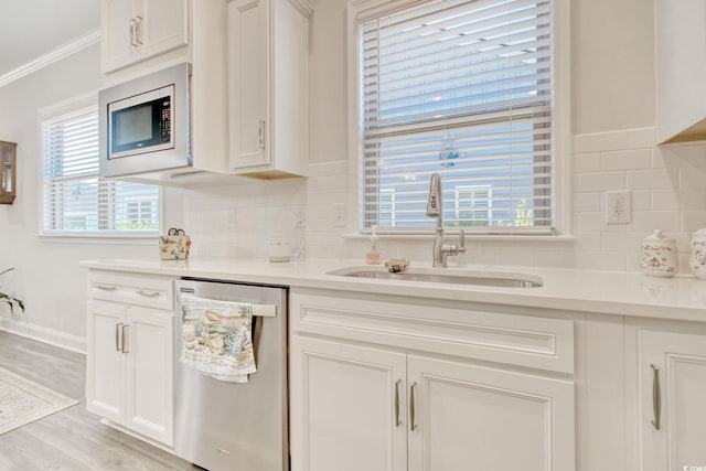 kitchen with sink, white cabinets, light wood-type flooring, and appliances with stainless steel finishes