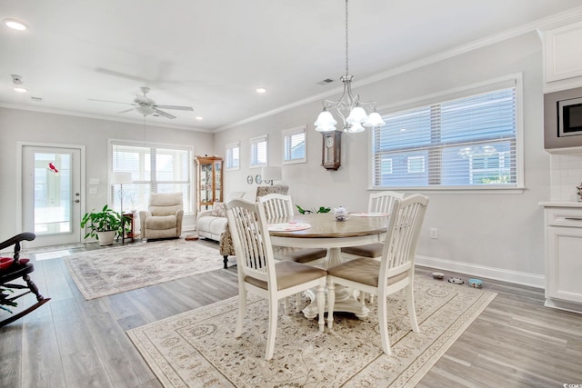 dining area with ceiling fan with notable chandelier, light wood-type flooring, and crown molding