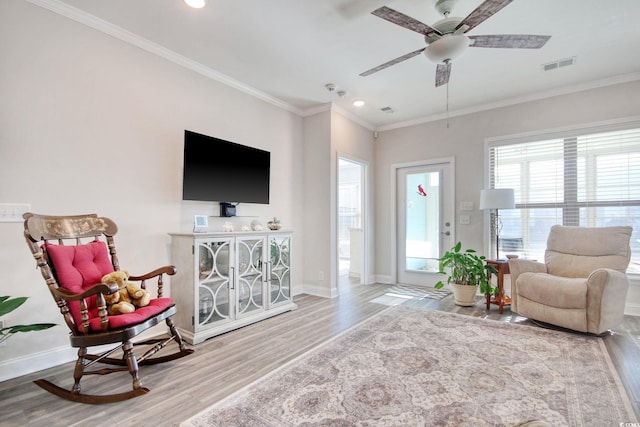 living area featuring hardwood / wood-style flooring, ceiling fan, and crown molding