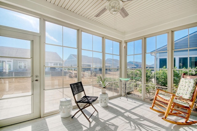 unfurnished sunroom featuring ceiling fan, a wealth of natural light, and a mountain view