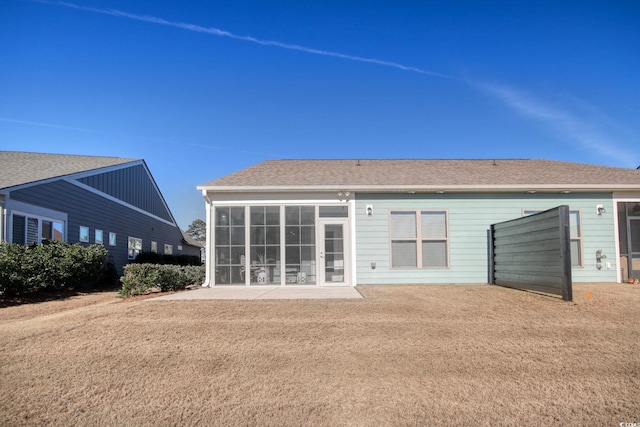 rear view of house featuring a patio, a yard, and a sunroom