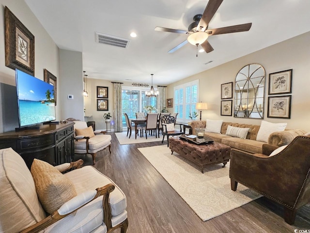 living room featuring ceiling fan with notable chandelier and dark hardwood / wood-style floors