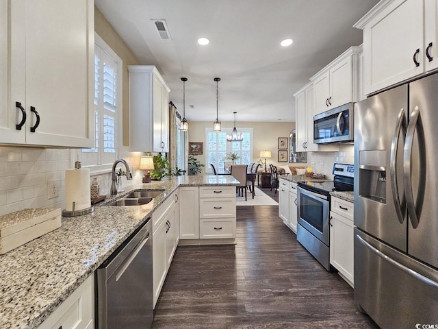 kitchen with kitchen peninsula, appliances with stainless steel finishes, white cabinets, and sink