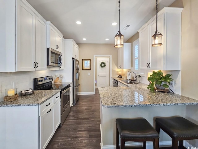 kitchen with kitchen peninsula, decorative light fixtures, stainless steel appliances, white cabinets, and sink