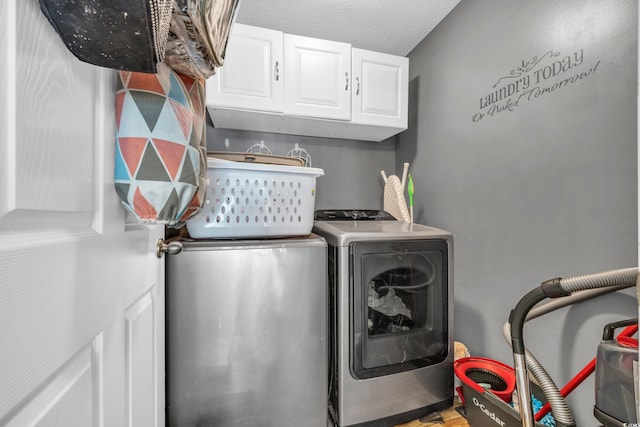 clothes washing area with a textured ceiling, cabinets, and independent washer and dryer