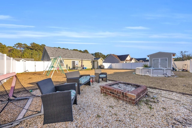 view of yard featuring a playground, a fenced in pool, and a shed