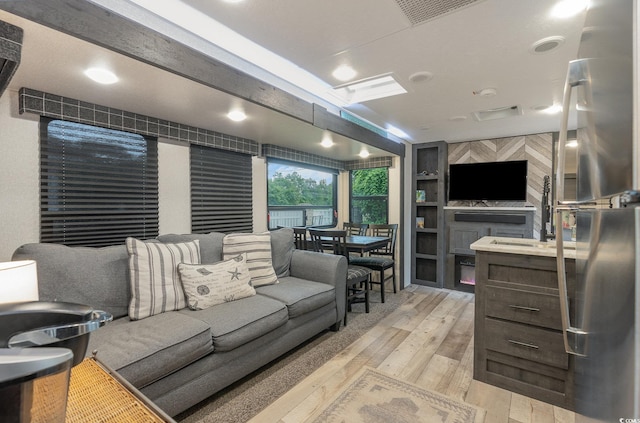 living room featuring light hardwood / wood-style floors, sink, and built in shelves