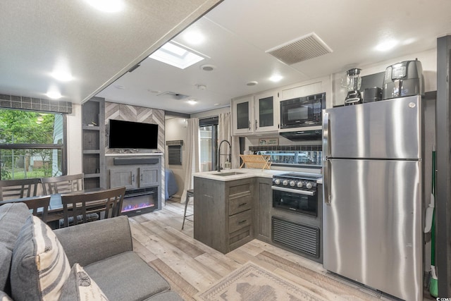 kitchen featuring sink, white cabinets, light hardwood / wood-style floors, kitchen peninsula, and appliances with stainless steel finishes