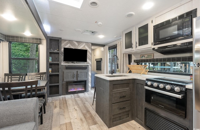 kitchen featuring white cabinetry, range, black microwave, sink, and light hardwood / wood-style flooring