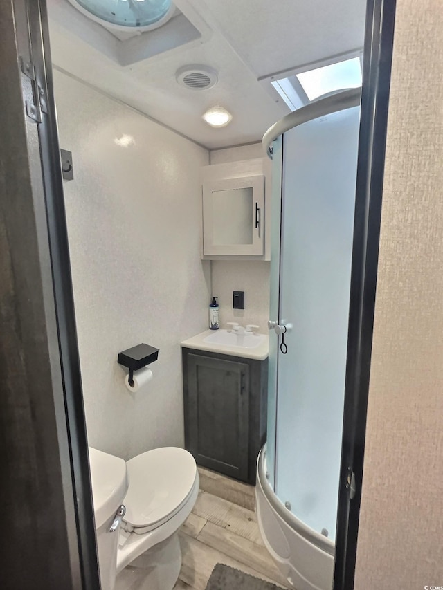 bathroom featuring toilet, vanity, hardwood / wood-style floors, and a shower with shower door