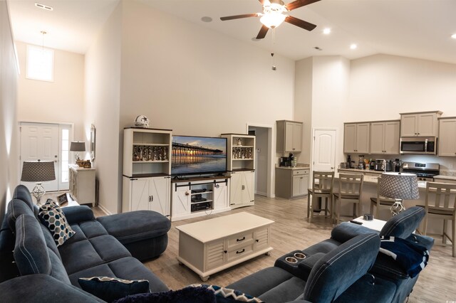 living room featuring ceiling fan, light wood-type flooring, and high vaulted ceiling