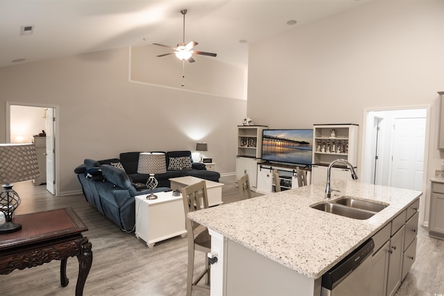 kitchen with sink, gray cabinetry, a center island with sink, light wood-type flooring, and stainless steel dishwasher