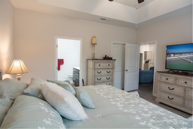 bedroom with light hardwood / wood-style floors, ensuite bathroom, and a tray ceiling