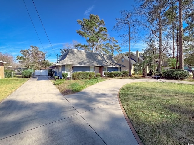 view of front facade featuring a front lawn, fence, and driveway