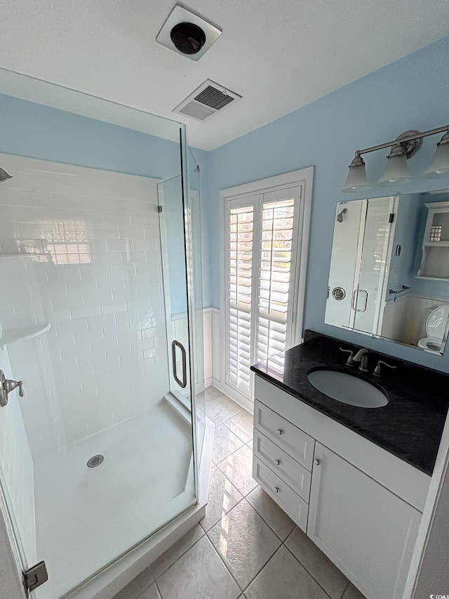 full bathroom featuring tile patterned floors, visible vents, a shower stall, and vanity