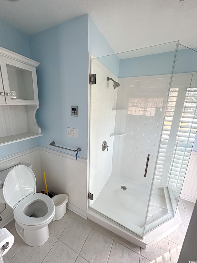 full bathroom with toilet, a shower stall, and tile patterned flooring