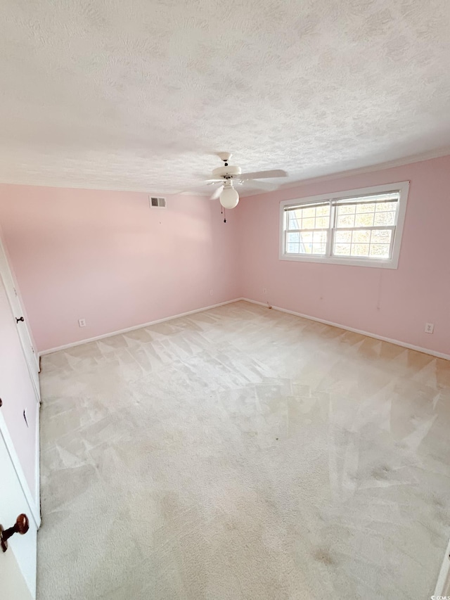 spare room with a ceiling fan, a textured ceiling, and visible vents