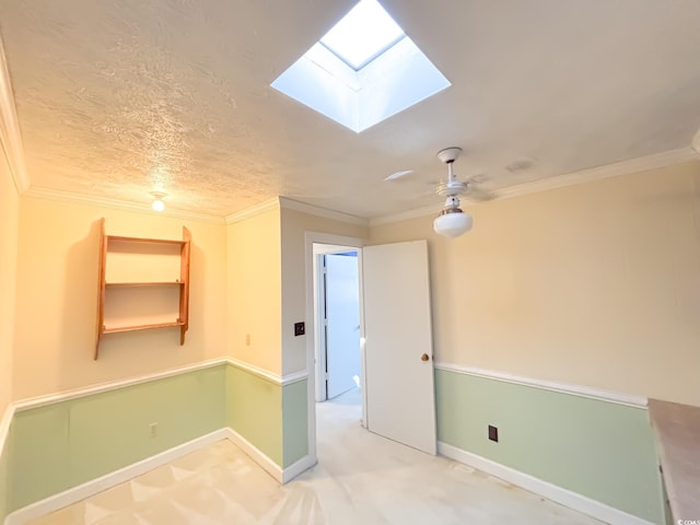 unfurnished room with carpet floors, a skylight, ornamental molding, and baseboards
