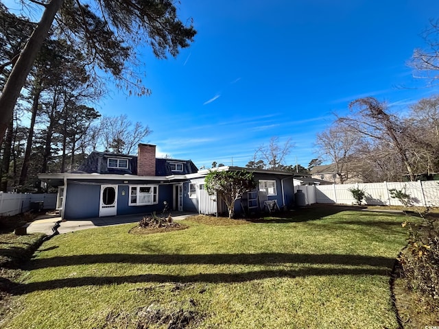 back of property with a lawn, fence, a chimney, and a patio area