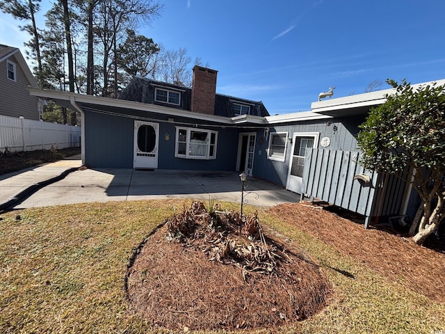 back of property featuring a patio, a lawn, fence, and a chimney