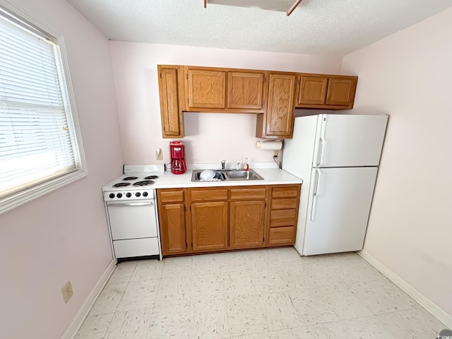 kitchen with brown cabinets, a sink, light countertops, light floors, and white appliances