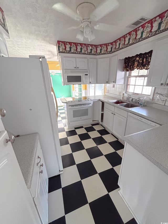 kitchen featuring ceiling fan, a sink, white appliances, light floors, and visible vents