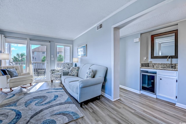 living area with ornamental molding, wine cooler, indoor wet bar, and visible vents