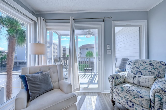 sitting room with a textured ceiling, wood finished floors, and crown molding