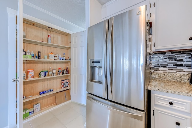 kitchen featuring stainless steel fridge, tasteful backsplash, light stone countertops, white cabinetry, and light tile patterned flooring