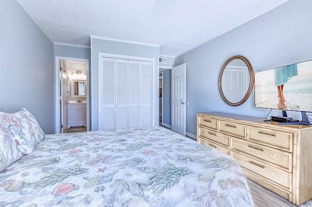 bedroom with a textured ceiling, a closet, ensuite bathroom, and crown molding