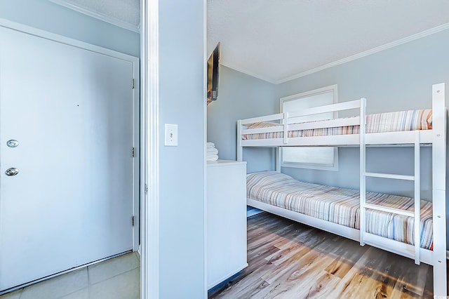 unfurnished bedroom with a textured ceiling, ornamental molding, and wood finished floors