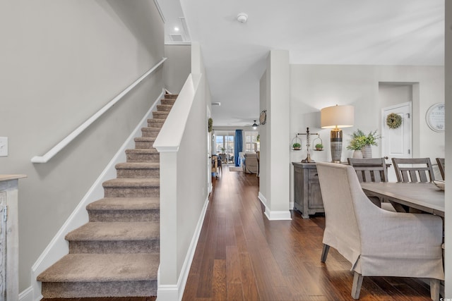 interior space featuring dark wood-style floors, stairs, a ceiling fan, and baseboards