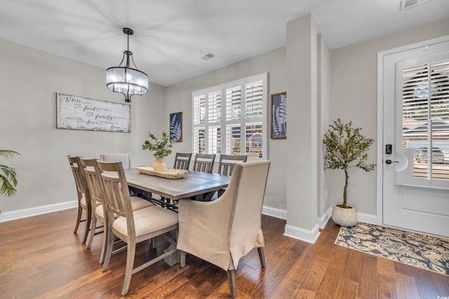 dining space featuring a notable chandelier, dark wood-style flooring, visible vents, and baseboards