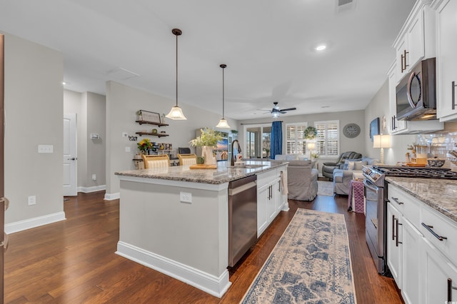 kitchen featuring an island with sink, white cabinetry, stainless steel appliances, and light stone counters