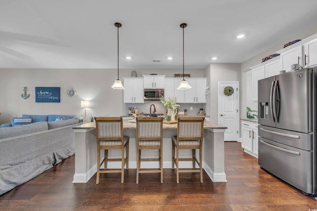 kitchen with an island with sink, white cabinetry, appliances with stainless steel finishes, and pendant lighting