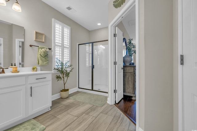 bathroom featuring vanity, baseboards, visible vents, wood tiled floor, and a stall shower