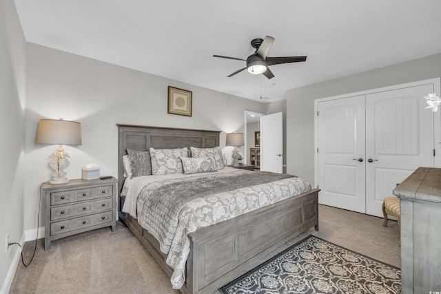 bedroom with light carpet, ceiling fan, baseboards, and a closet