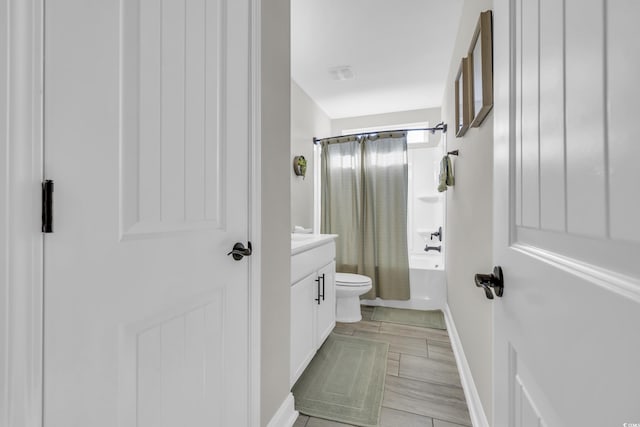 full bathroom featuring shower / tub combo, baseboards, vanity, and toilet