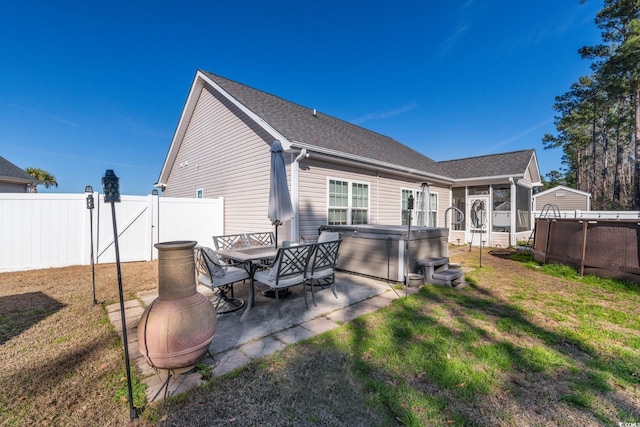 rear view of property with a sunroom, a pool with hot tub, a patio, and a lawn