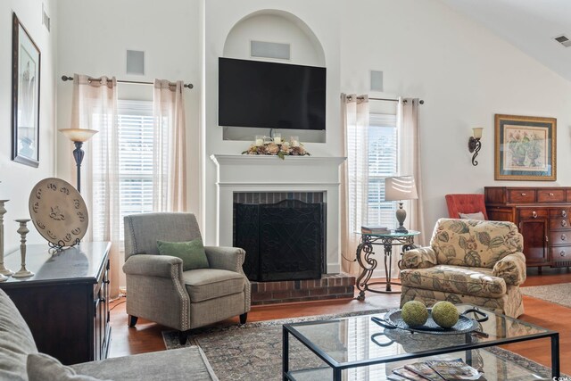 living room with a brick fireplace, a wealth of natural light, lofted ceiling, and dark hardwood / wood-style floors