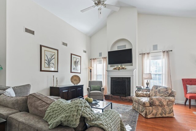 living room with hardwood / wood-style flooring, high vaulted ceiling, ceiling fan, and a fireplace